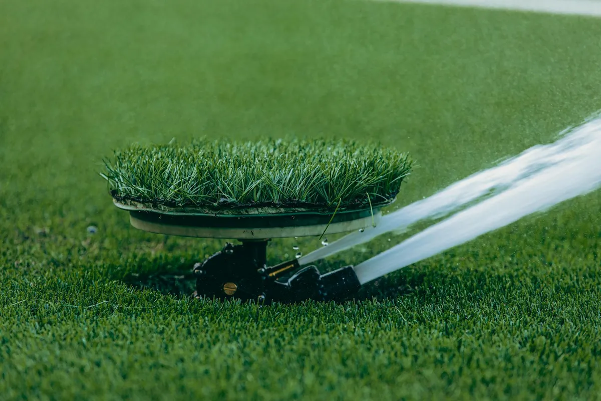 A modern smart sprinkler watering a green lawn